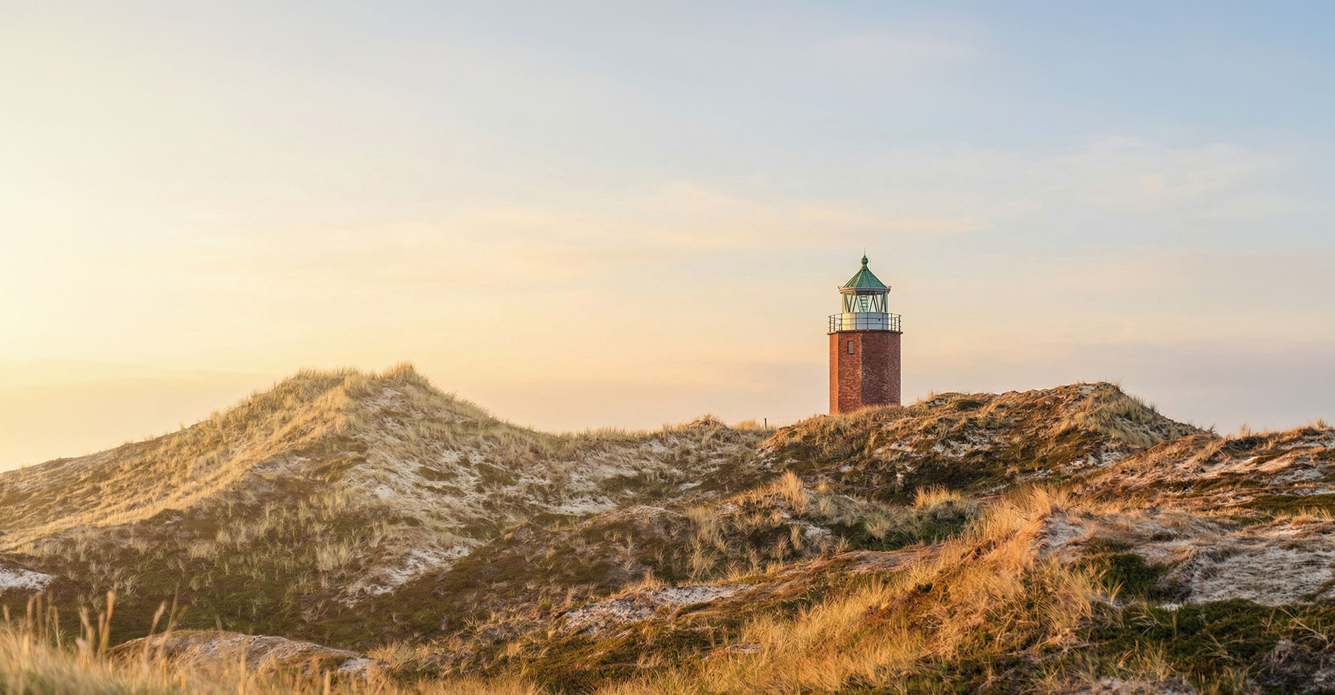 Ein Leuchtturm in den Sylter Dünen bei Sonnenuntergang